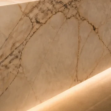 Warm white stone face with fine veins above a soft line of light