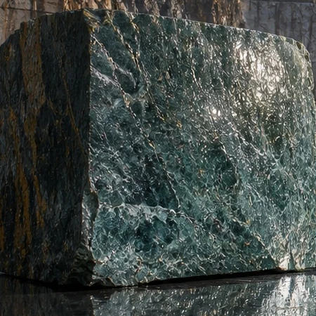 Rough block of deep green stone with dark veins, wet from the quarry